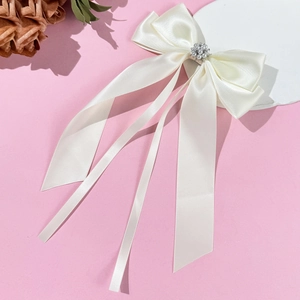 Dettaglio del fiocco in raso crema con decorazione centrale di perle e strass eleganti