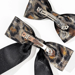 Detail view of leopard print bow hair clip showing the CLIP PARIS engraved metal spring base