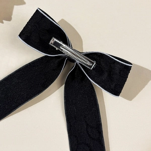 Vue détaillée de la barrette nœud en velours noir avec liseré blanc et clip bec de canard
