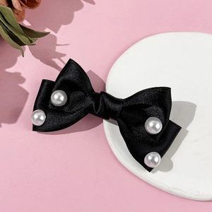 Close-up of black satin bow hair clip decorated with four elegant white pearls