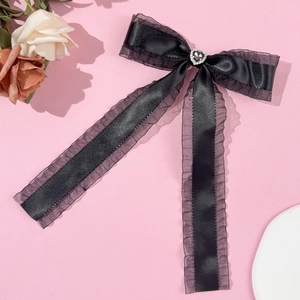 Detail of black bow hair clip featuring a heart rhinestone and elegant long ribbons