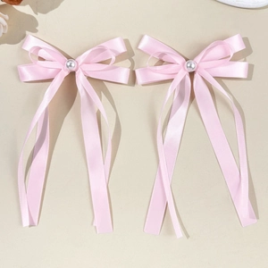 Gros plan de nœuds en satin rose avec perles centrales et rubans élégants