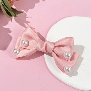 Detail of pink satin ribbon bow hair clip with pearl accents on a white display stand