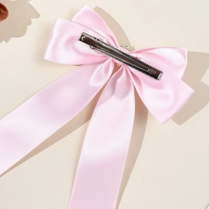 Détail de la pince à cheveux nœud en satin rose avec longs rubans élégants et clip métallique