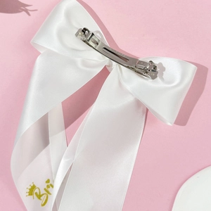 Nahaufnahme der weißen Satin-Brautschleife mit goldenem Bride-Schriftzug und Metallclip