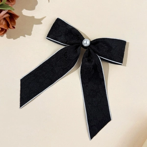 Détail de la barrette à cheveux nœud en dentelle noire avec perle et bord argenté