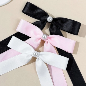 Detailed close-up of satin bow hair clips with pearls in black, pink, and white