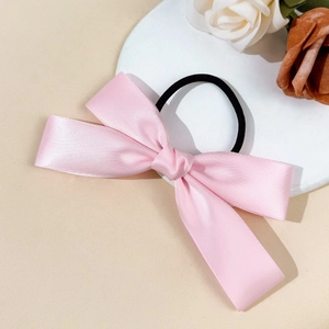 Detail van roze satijnen strik haarelastiek op een witte standaard met bloemen