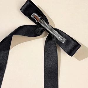 Detailed macro view of black satin bow hair clip with silver metal alligator clip mechanism