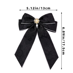 Close-up of black lace bow hair clip with pearl centerpiece and rhinestone details
