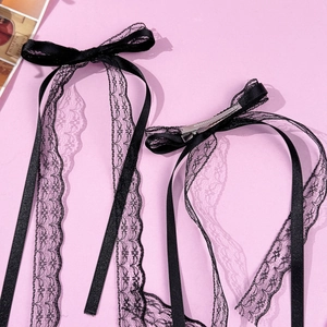 Detail of black lace bow hair clip with long ribbons and silver metal duckbill clip
