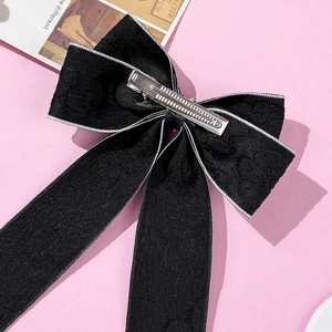 Detail view of black jacquard bow hair clip with silver metal duckbill clip back