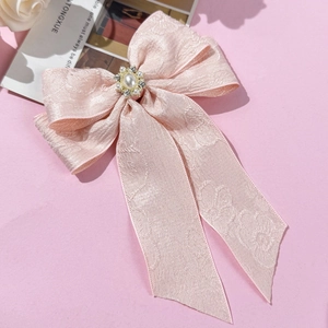 Macro detail of a large pink jacquard ribbon hair clip with pearl and rhinestone center