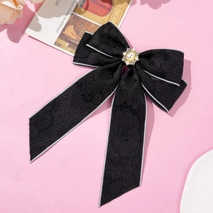 Close-up of black lace bow hair clip with central pearl and rhinestone details