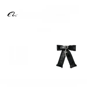 Détail d'une pince à cheveux gothique avec nœud noir, boucle cœur et pendentif croix