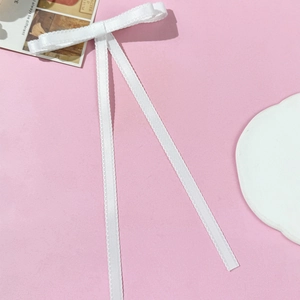 Elegant white lace ribbon bow hair clip on a minimalist pink background for women