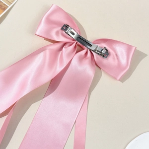Détail du nœud en satin rose montrant le clip en métal argenté et la texture du tissu