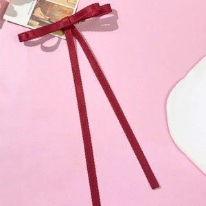 Close-up of wine red lace bow hair clip with textured ribbon and scalloped edges