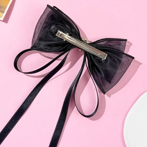 Dettaglio del fermaglio per capelli a fiocco in tulle nero con nastri lunghi e clip in metallo