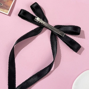 Détail d'une pince à cheveux en soie noire avec bords ondulés et clip en métal argenté