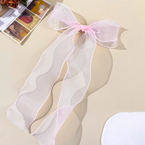 Pink sheer organza bow hair clip with long ribbons on a minimalist warm beige background