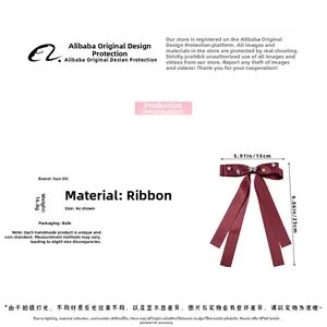 Detailed view of red bow hair clip with rhinestones and long flowing ribbons