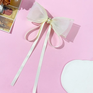 Dettaglio del fermaglio a fiocco color crema con organza, perle e strass eleganti