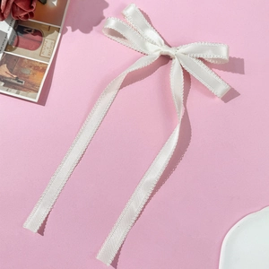 Détail d'une pince à cheveux en satin blanc avec bordures en dentelle et rubans