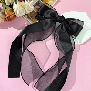 Detail of elegant black layered organza bow hair clip with long flowing ribbons