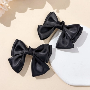 Close-up of black satin bow hair clips showing elegant double-layered fabric texture