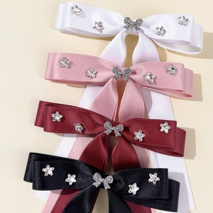 Detailed view of satin bow hair clips with sparkling rhinestone stars in four colors