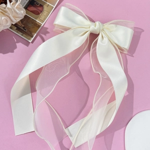 Detail of elegant cream ribbon bow hair clip with double-layer organza and long streamers