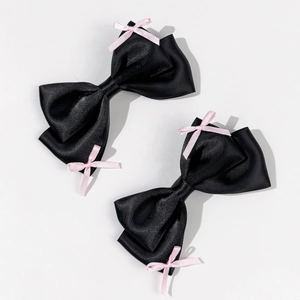 Detail of sweet bow hair clips with black satin fabric and small pink ribbon accents