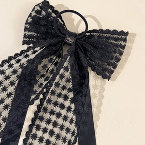 Détail d'un chouchou en dentelle noire avec grand noeud et rubans élégants