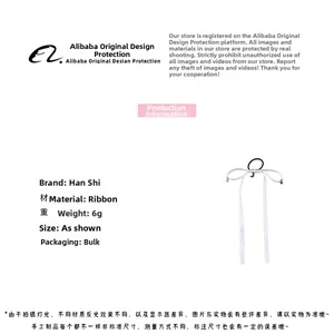 Detailed view of white satin ribbon hair tie with moon and star metal pendants