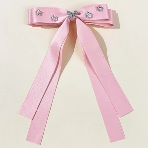Detailed close-up of pink satin bow hair clip with rhinestone butterfly and stars decoration