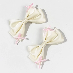 Pair of cream satin bow hair clips with tiny pink bow accents in a minimalist style