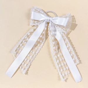 Détail du chouchou à nœud blanc en satin avec dentelle étoilée et longs rubans