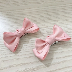 Details der hellrosa Schleifen-Haarspangen aus Satin mit glatter Textur und Metall-Clip