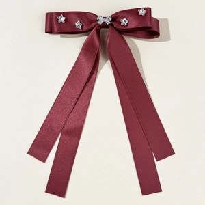 Detail of burgundy satin bow hair clip featuring star rhinestones and long elegant ribbons