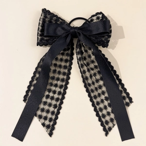 Détail d'un chouchou en dentelle noire élégante avec motif d'étoiles et ruban en satin
