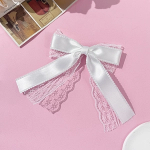 Elegant white lace and silk ribbon bow hair clip with long streamers on pink background