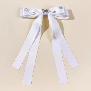 Detail of white satin bow hair clip with crystal butterfly and long flowing ribbons