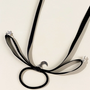 Detailed macro view of black ribbon hair tie with silver star and moon charms