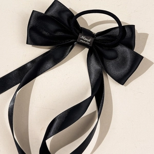 Detailed close-up of a handmade black satin ribbon bow scrunchie with long streamers