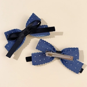 Detail view of blue denim bow hair clip with white polka dots and metal duckbill clip