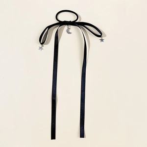 Detail of black velvet hair tie with silver star and moon charms on long ribbons