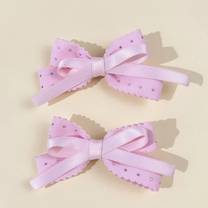 Pink satin bow hair clips set with sparkling rhinestones and elegant wavy edges