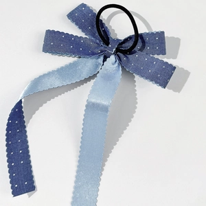Détail d'un chouchou noeud bleu à pois avec bords ondulés et élastique noir résistant
