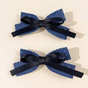 Detailed view of two denim and satin bow hair clips with sparkling rhinestone accents